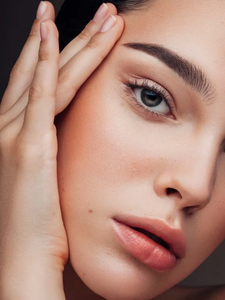 Mujer con las manos en el rostro, piel natural y cuidada