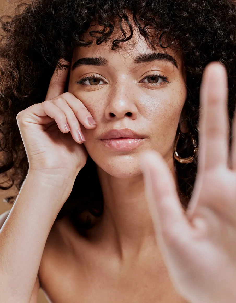 Mujer de piel natural con la mano junto al rostro