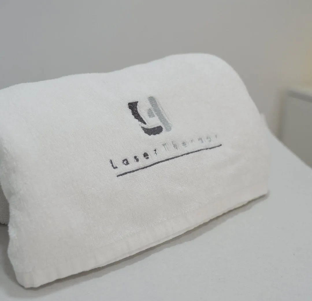 Toalla con el logotipo de Laser Therapy sobre la camilla de tratamiento